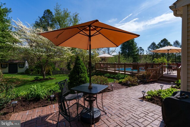 view of patio / terrace featuring an outdoor structure, a fenced in pool, outdoor dining space, a deck, and fence