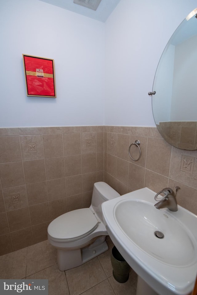 bathroom with a sink, tile walls, tile patterned flooring, and toilet