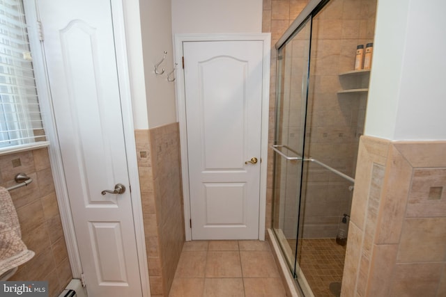 full bath with tile walls, a shower stall, tile patterned flooring, and a wainscoted wall