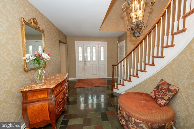foyer featuring wallpapered walls, stairs, and a chandelier