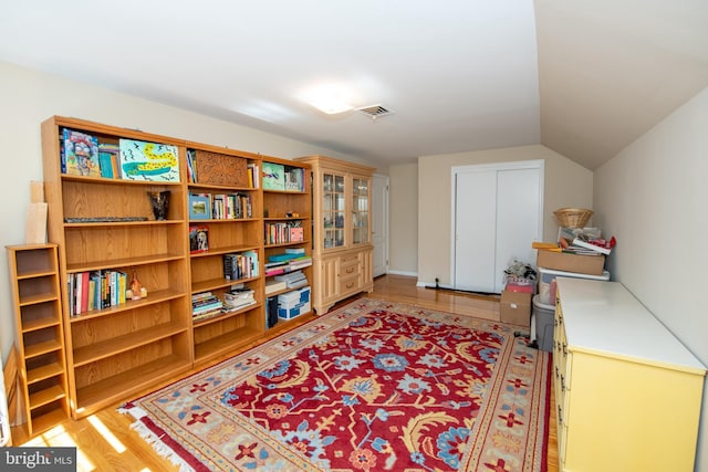 living area featuring visible vents, light wood finished floors, and lofted ceiling