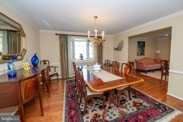 dining area featuring light wood-style floors, baseboards, crown molding, and a chandelier
