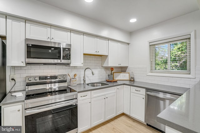 kitchen featuring white cabinets, a sink, stainless steel appliances, recessed lighting, and backsplash