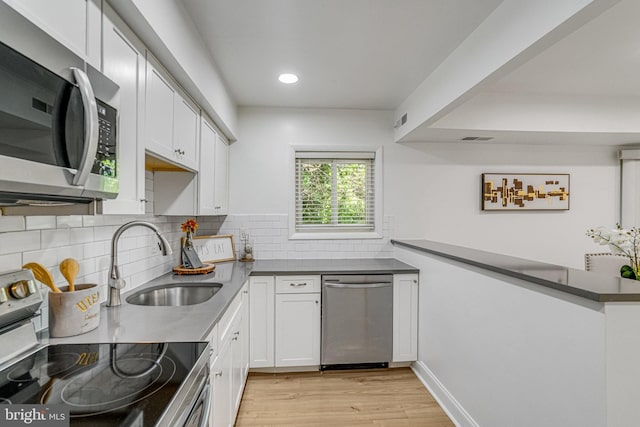 kitchen featuring a sink, appliances with stainless steel finishes, light wood finished floors, and white cabinetry