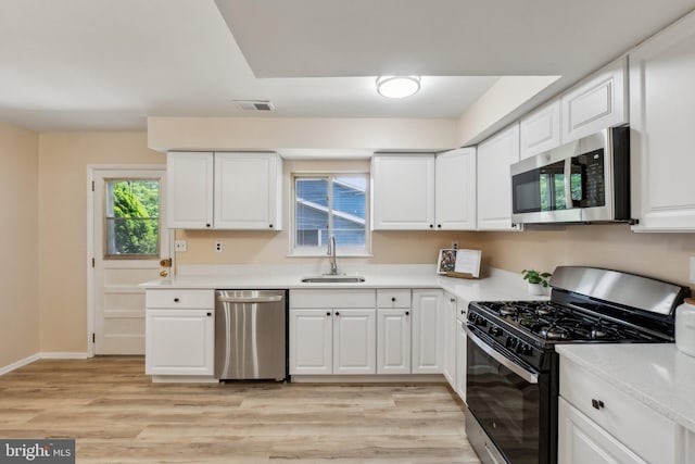 kitchen with stainless steel appliances, visible vents, a sink, white cabinetry, and light countertops