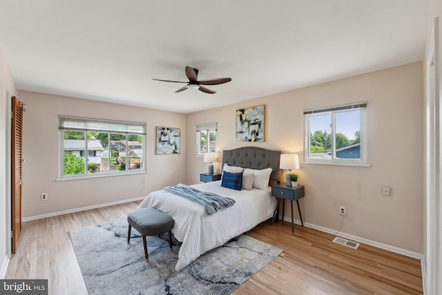 bedroom with baseboards, light wood-type flooring, visible vents, and multiple windows