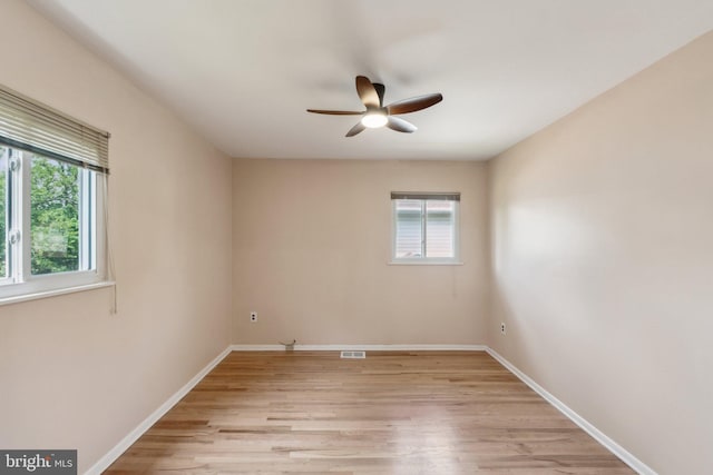 spare room with baseboards, visible vents, light wood-style flooring, and ceiling fan