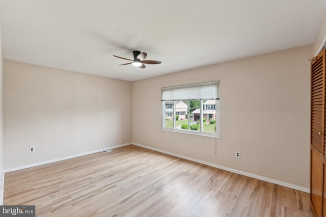 spare room featuring light wood-style floors, visible vents, baseboards, and a ceiling fan
