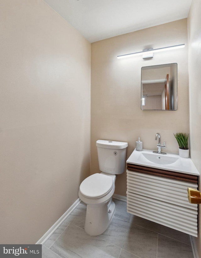 bathroom with toilet, baseboards, tile patterned floors, and vanity