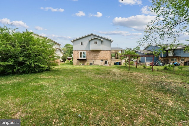 rear view of property with a yard, brick siding, and fence