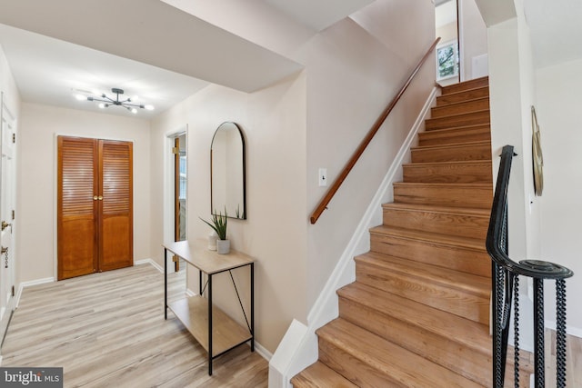 entrance foyer featuring a chandelier, stairs, baseboards, and light wood-type flooring
