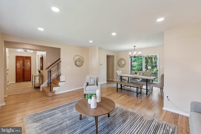 living area featuring a chandelier, baseboards, and light wood-style floors
