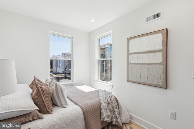 bedroom with baseboards, wood finished floors, visible vents, and recessed lighting