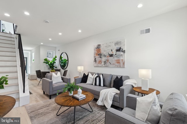 living room featuring wood finished floors, stairs, visible vents, and recessed lighting