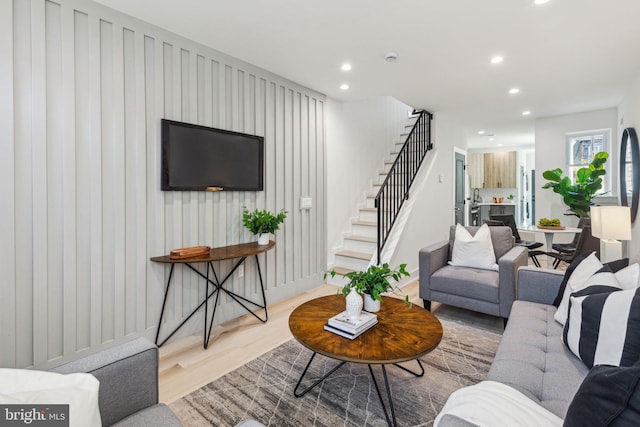living area featuring recessed lighting, wood finished floors, baseboards, and stairs