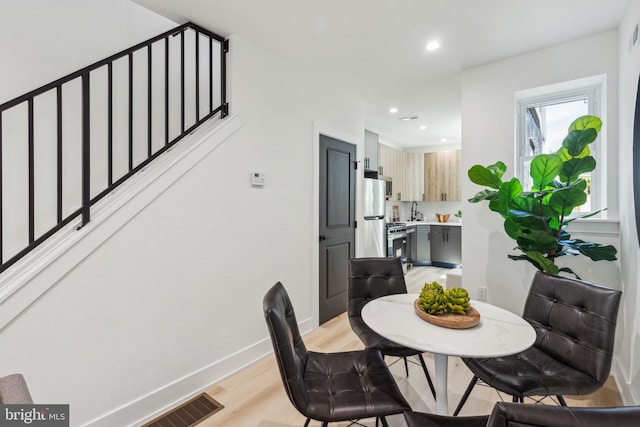 dining room featuring baseboards, stairs, light wood finished floors, and recessed lighting
