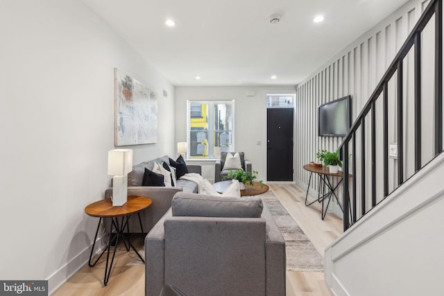 living area featuring recessed lighting, light wood-type flooring, stairs, and baseboards
