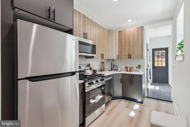 kitchen with recessed lighting, a sink, light wood-style floors, tasteful backsplash, and appliances with stainless steel finishes