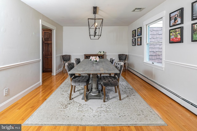 dining room with baseboard heating, wood finished floors, baseboards, and a chandelier