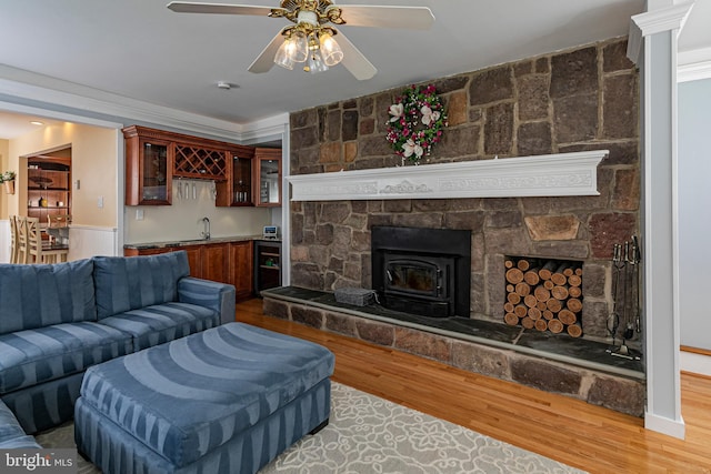 living area featuring wet bar, wood finished floors, a ceiling fan, a wood stove, and wine cooler