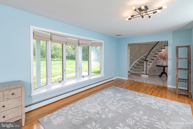 living room with a baseboard radiator, stairway, a chandelier, and baseboards