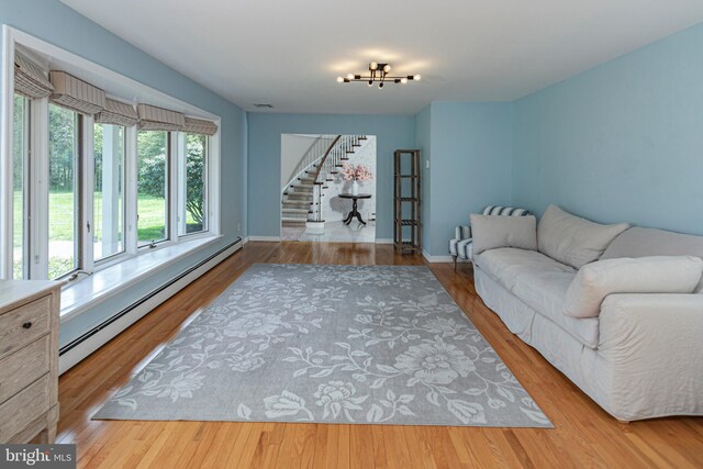 living room featuring a baseboard radiator, stairs, wood finished floors, and baseboards