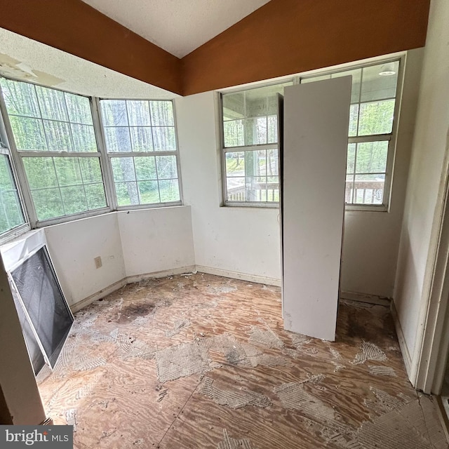 empty room featuring vaulted ceiling and baseboards