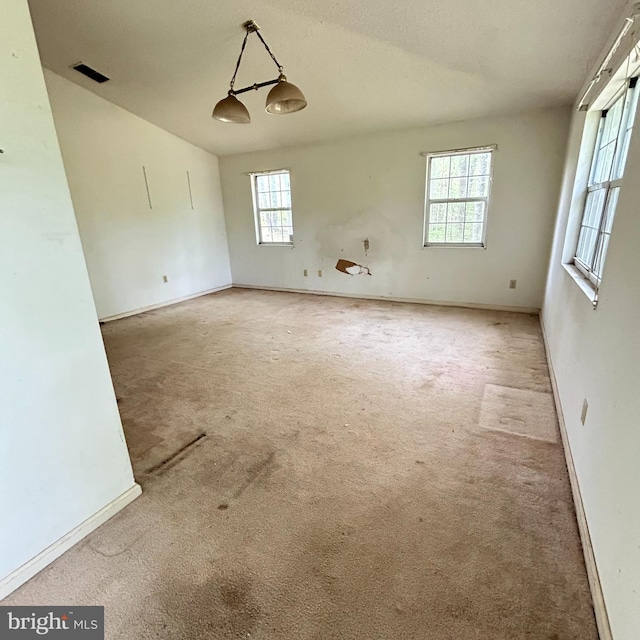carpeted empty room featuring baseboards and visible vents