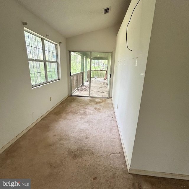 interior space featuring lofted ceiling, visible vents, baseboards, and a healthy amount of sunlight