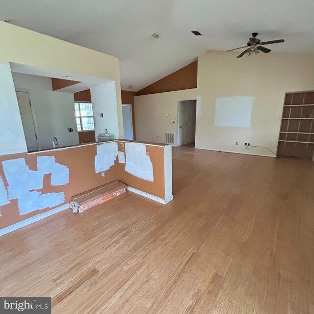 empty room with lofted ceiling, wood finished floors, visible vents, and ceiling fan