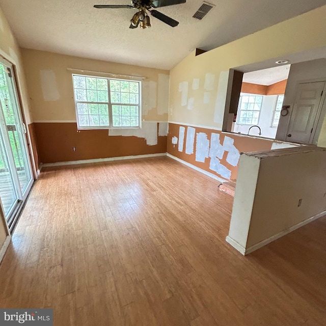 empty room featuring wood finished floors, visible vents, a ceiling fan, and plenty of natural light