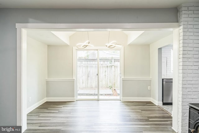 unfurnished dining area with baseboards, a chandelier, wood finished floors, and a fireplace