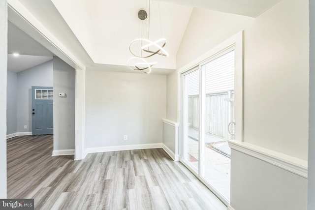 unfurnished dining area featuring lofted ceiling, light wood finished floors, baseboards, and an inviting chandelier