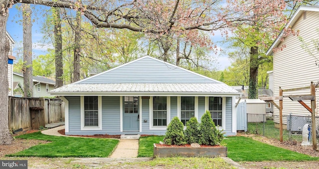 bungalow-style home with fence, a front lawn, covered porch, and metal roof