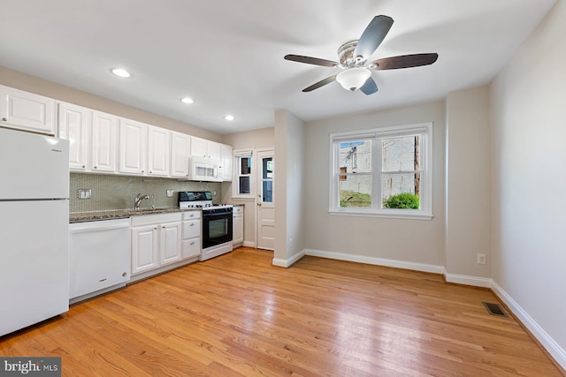 kitchen featuring a sink, white cabinets, light wood-type flooring, and white appliances