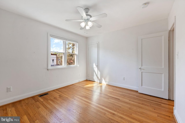 empty room featuring baseboards, a ceiling fan, light wood finished floors, and visible vents