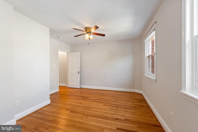 spare room featuring ceiling fan, baseboards, and light wood-style floors
