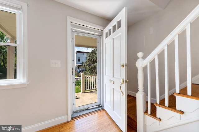 entrance foyer with light wood-style floors, baseboards, and stairway