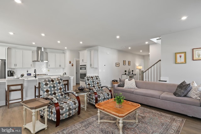 living area with stairs, wood finished floors, and recessed lighting