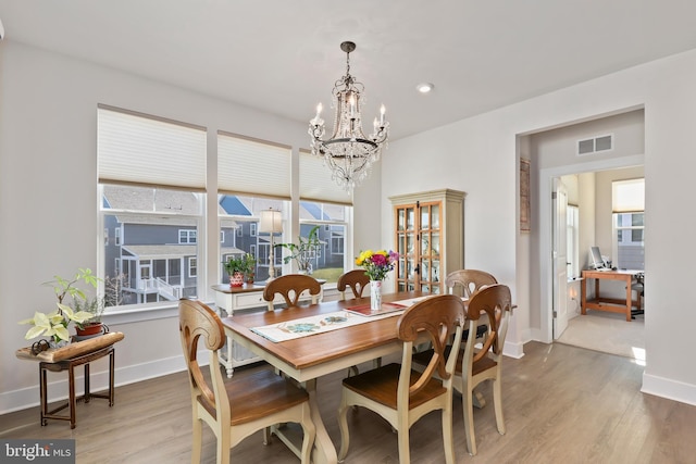 dining area with baseboards, a notable chandelier, wood finished floors, and visible vents