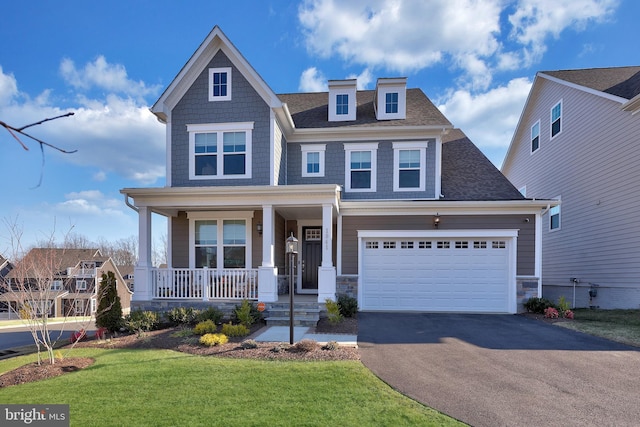 craftsman-style home with aphalt driveway, a front lawn, a porch, roof with shingles, and stone siding