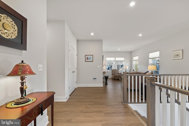 hall featuring baseboards, wood finished floors, an upstairs landing, and recessed lighting