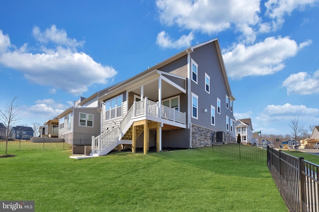 rear view of house with stairway, a fenced backyard, a yard, and a residential view