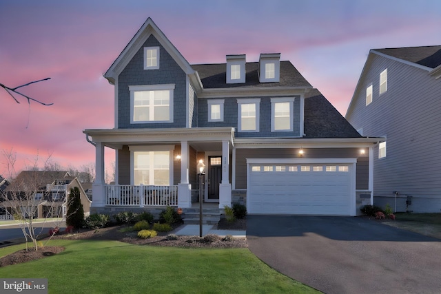 view of front of property with an attached garage, a lawn, covered porch, and aphalt driveway