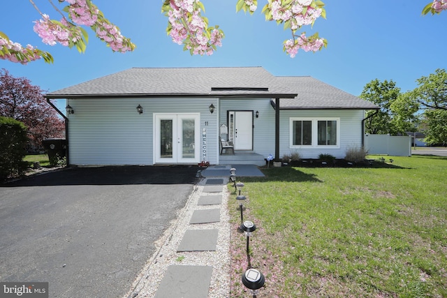 view of front of house with french doors, a shingled roof, and a front lawn