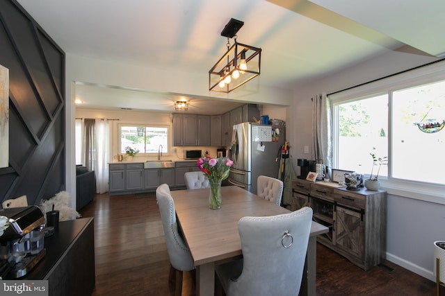 dining space with dark wood-type flooring, baseboards, and a chandelier