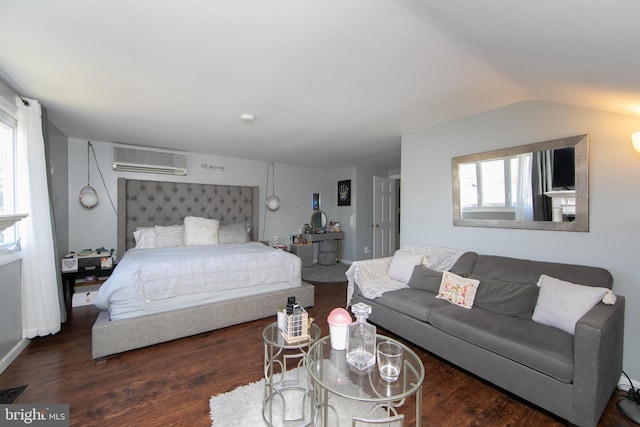 bedroom with wood finished floors, lofted ceiling, and a wall unit AC