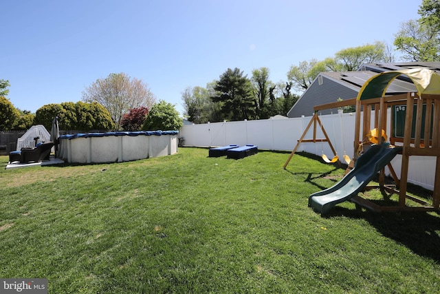 view of yard featuring a fenced in pool, a fenced backyard, and a playground