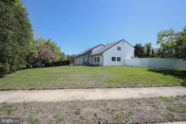 view of side of home featuring a lawn and fence