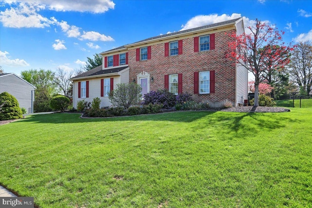 colonial house with a front yard and brick siding